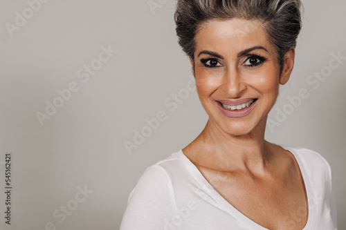 Beautiful senior woman with makeup looking and smiling at camera