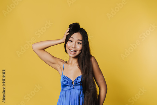 Young asian woman wearing dress smiling and looking at camera