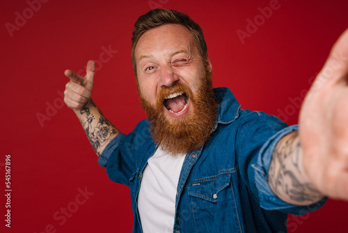 Selfie of adult bearded tattooed handsome enthusiastic redhead man