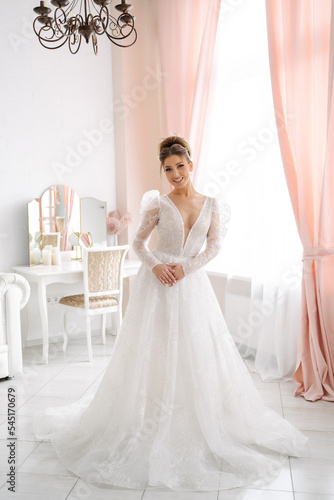 beautiful bride in an expensive wedding dress in full growth posing in a bright interior