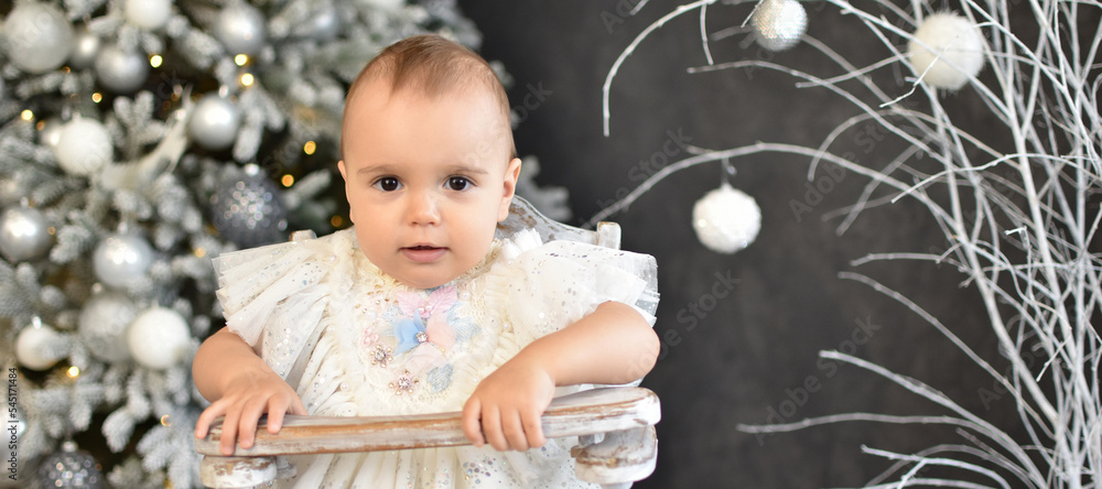 Naklejka premium Cute little baby against blurred lights on dark background. Christmas celebration