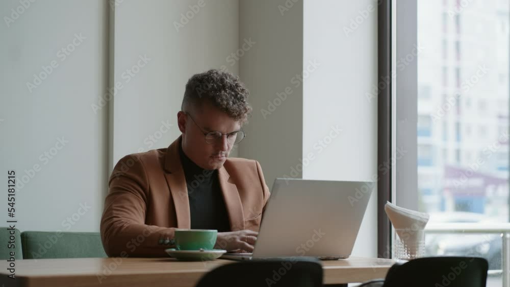 stylish handsome man is working with laptop in cafe, freelancer or office worker on remote job stylish handsome man is working with laptop in cafe, freelancer or office worker on remote job