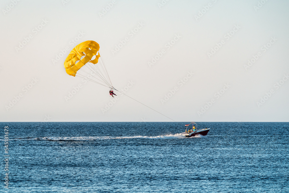 Parasailing by boat water amusement. Flying on a parachute behind a boat on a summer holiday Parasailing by boat water amusement. Flying on a parachute behind a boat on a summer holiday