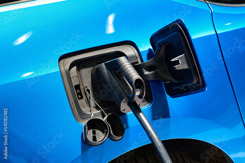 Charging electric blue automobile with plug at power station