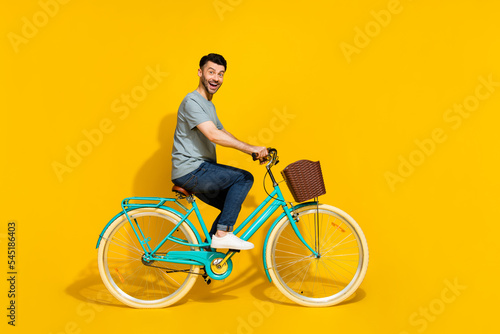 Side profile photo of young crazy positive good mood day man riding new bicycle rent chill hobby weekend isolated on bright yellow color background