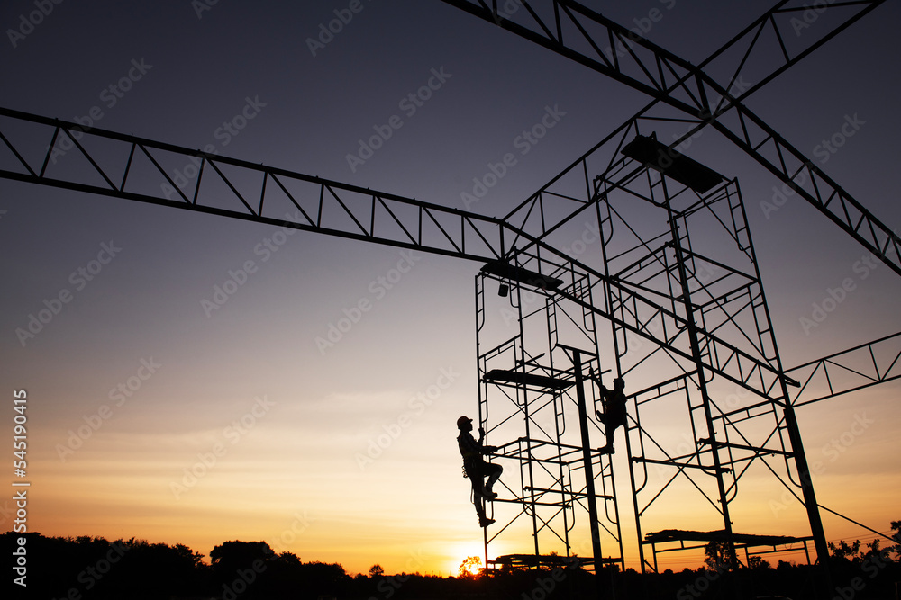 teamwork construction worker installation scaffolding in industrial construction sunset sky background overtime job Silhouette.