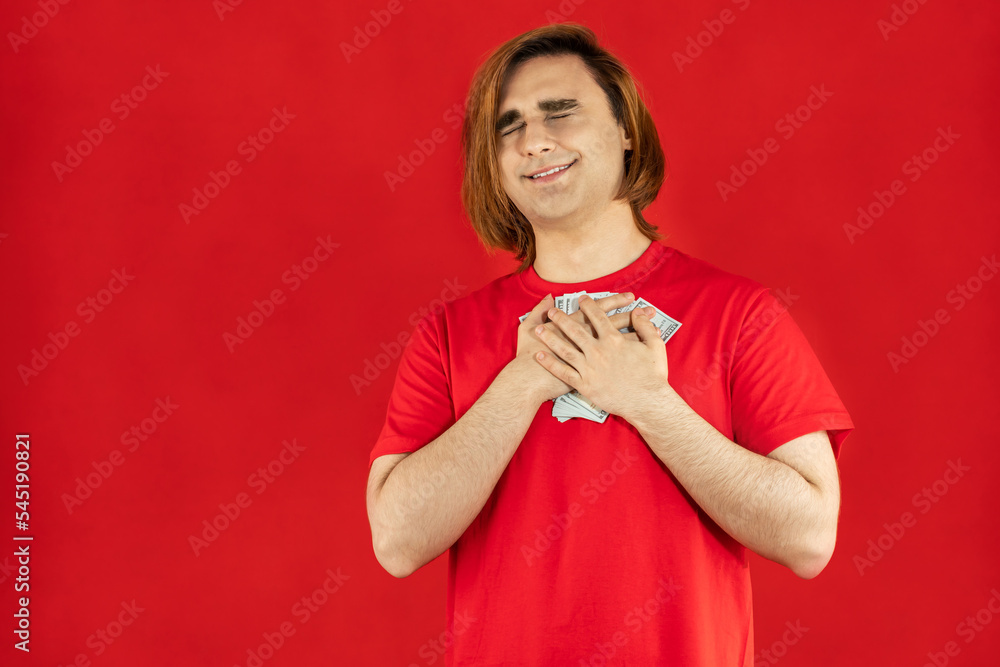 Emotional young man with cash. Guy with currency banknotes. The concept of a successful money story, start-up, student loan, part-time job, winning Emotional young man with cash. Guy with currency banknotes. The concept of a successful money story, start-up, student loan, part-time job, winning