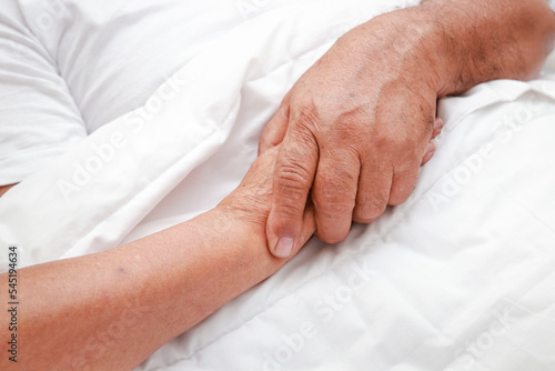 Asian elderly couple sleeping holding hands in bed in the bedroom. family concept health care, health insurance for seniors