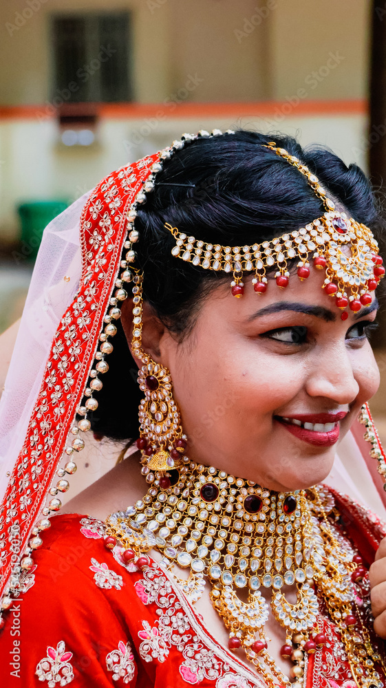 Portrait of a beautiful Indian bride in a traditional wedding dress. Young Hindu woman with golden Kundan jewelry set. Traditional Indian costume lehenga choli.  kalira and red nail paint