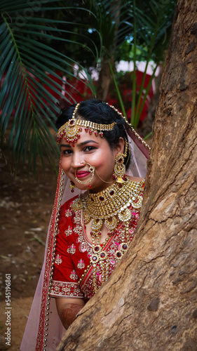 Portrait of a beautiful Indian bride in a traditional wedding dress. Young Hindu woman with golden Kundan jewelry set. Traditional Indian costume lehenga choli. kalira and red nail paint