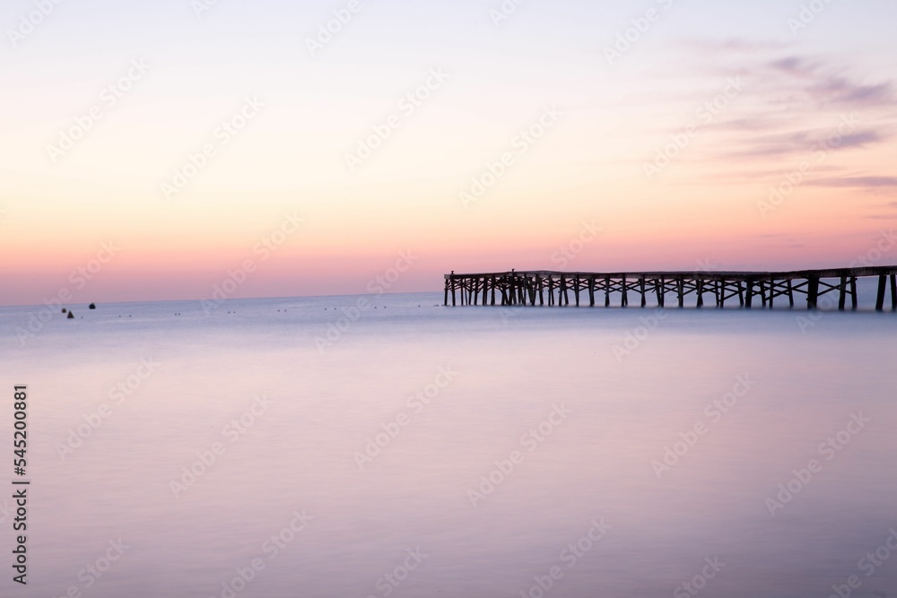 Long pier in the sea at sunset