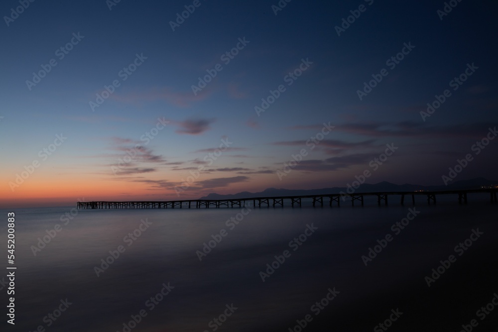 Long pier in the sea at sunset
