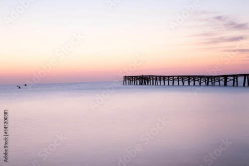 Long pier in the sea at sunset © Frozen Moment/Wirestock Creators