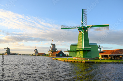 Old windmills by the river in Netherlands. Traditional Windmill during sunset. Oil mill in Zaanse Schans.