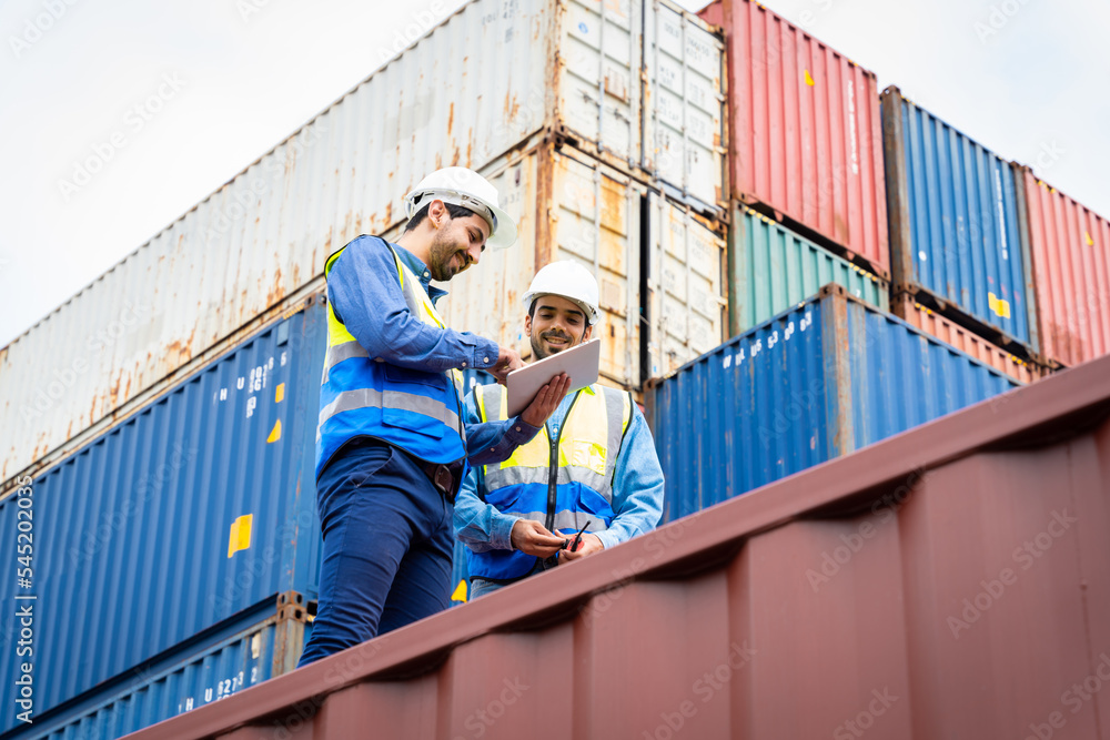 Two male engineers in a container shipping company Consulting to check the order for the container that is responsible