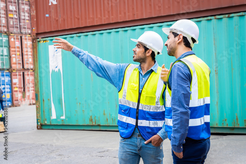 Two male engineers in a container shipping company Consulting to check the order for the container that is responsible