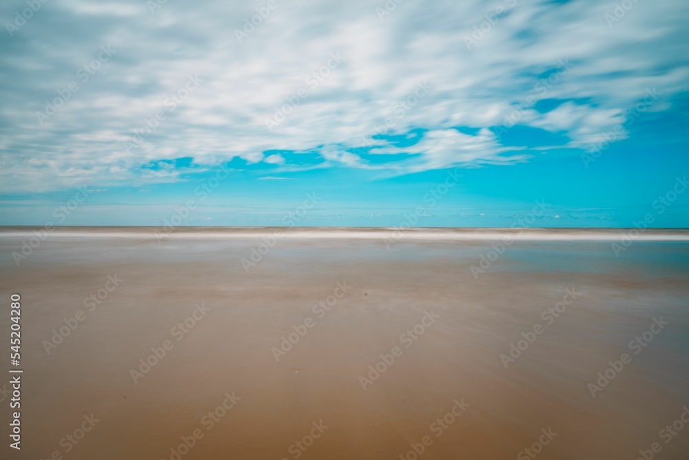 Scenic view of a beautiful sandy beach against a blue cloudy sky in Zandvoort