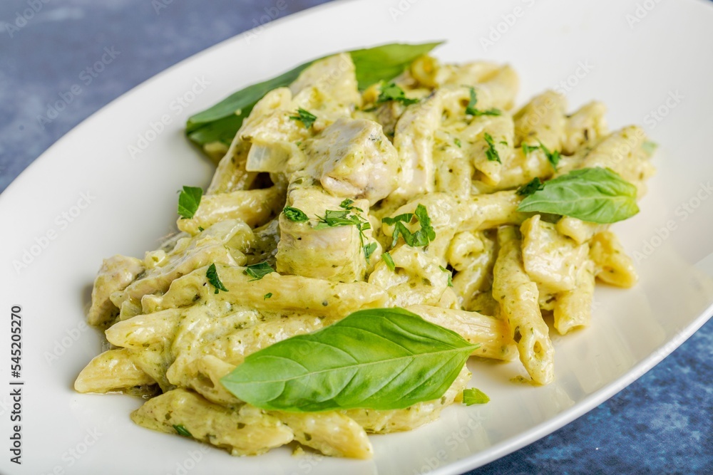 Nice shot of penne pasta with white sauce decorated with basil leaves on a white plate Nice shot of penne pasta with white sauce decorated with basil leaves on a white plate