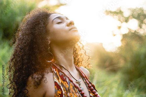 Imagen horizontal de cerca de una hermosa mujer latina al aire libre disfrutando de un atardecer mientras practica yoga y medita.  
