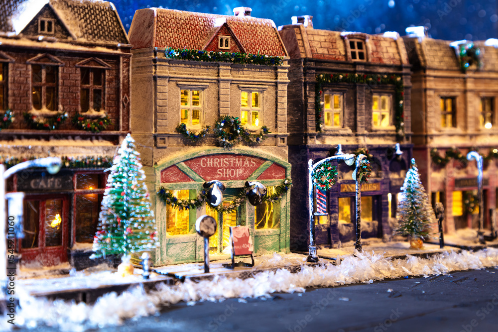 Night snow-covered European street decorated for Christmas. Homemade decorated toy houses.