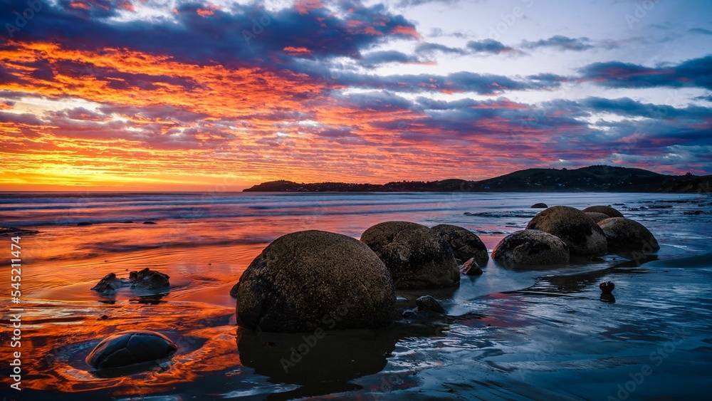 Obraz premium Scenic view of Moeraki Boulders Beach in Hampden, New Zealand at sunset