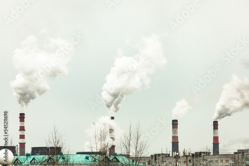 industrial chimneys with heavy smoke causing air pollution on the gray smoky sky background 