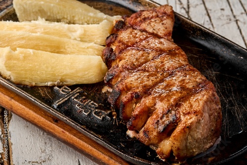 Top view of a chicken steak and Yuca sancochada on a wooden table