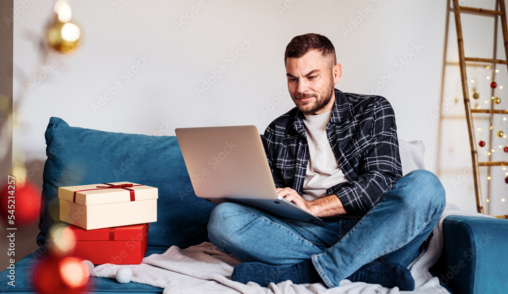 Man using his laptop at home during christmas holiday.