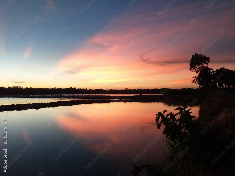 Obraz premium Dramatic scenery of a beautiful sunset in the cloudy sky over the lake in Bangladesh