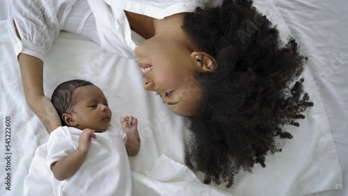 Closeup portrait of beautiful young African American mother day girl kiss healthy newborn baby sleep in bed flat lay copy space. Healthcare medical love black woman lifestyle mother's day, top view