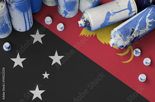 Papua New Guinea flag and few used aerosol spray cans for graffiti painting. Street art culture concept photo