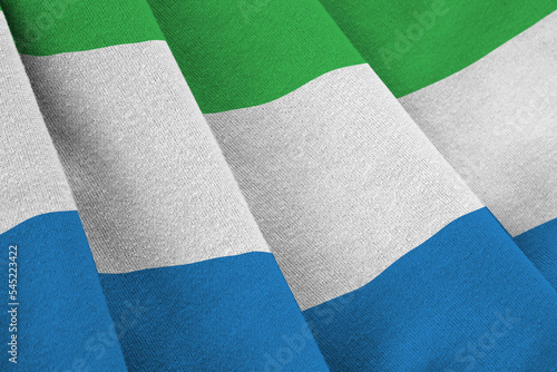 Sierra Leone flag with big folds waving close up under the studio light indoors. The official symbols and colors in banner photo