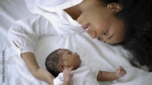 Closeup portrait of beautiful young African American mother day girl kiss healthy newborn baby sleep in bed flat lay copy space. Healthcare medical love black woman lifestyle mother's day, top view