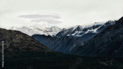 Scenic shot of a high mountain range with snowy peaks under the clear sky