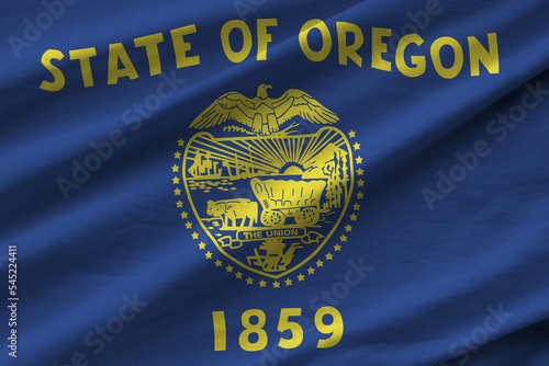 Oregon US state flag with big folds waving close up under the studio light indoors. The official symbols and colors in banner photo