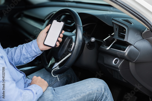 Close-up shot of the driver using a smartphone with a blank white screen inside the car. Man looking at location, finds smartphone screen through gps navigator application. © Witoon
