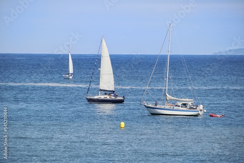Closeup shot of white boats sailing along the Galician coasts of the Cantabrian Sea