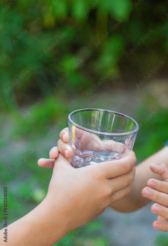 The child drinks water from a glass. Selective focus. The child drinks water from a glass. Selective focus.