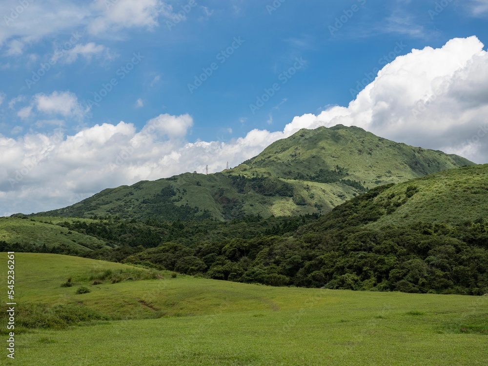 Green landscape with mountains and a cloudscape in the background