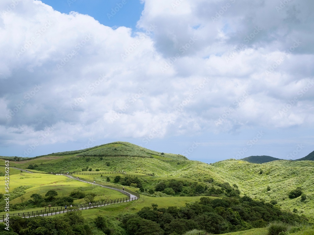 Obraz premium Green landscape with mountains and a cloudscape in the background