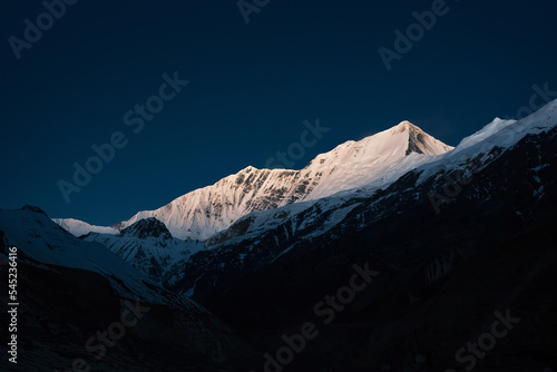 White snow covered mountains against dark blue sky. Mountain landscape in Dhaulagiri base camp, Myagdi region, Nepal. Himalaya mountains after sunset.