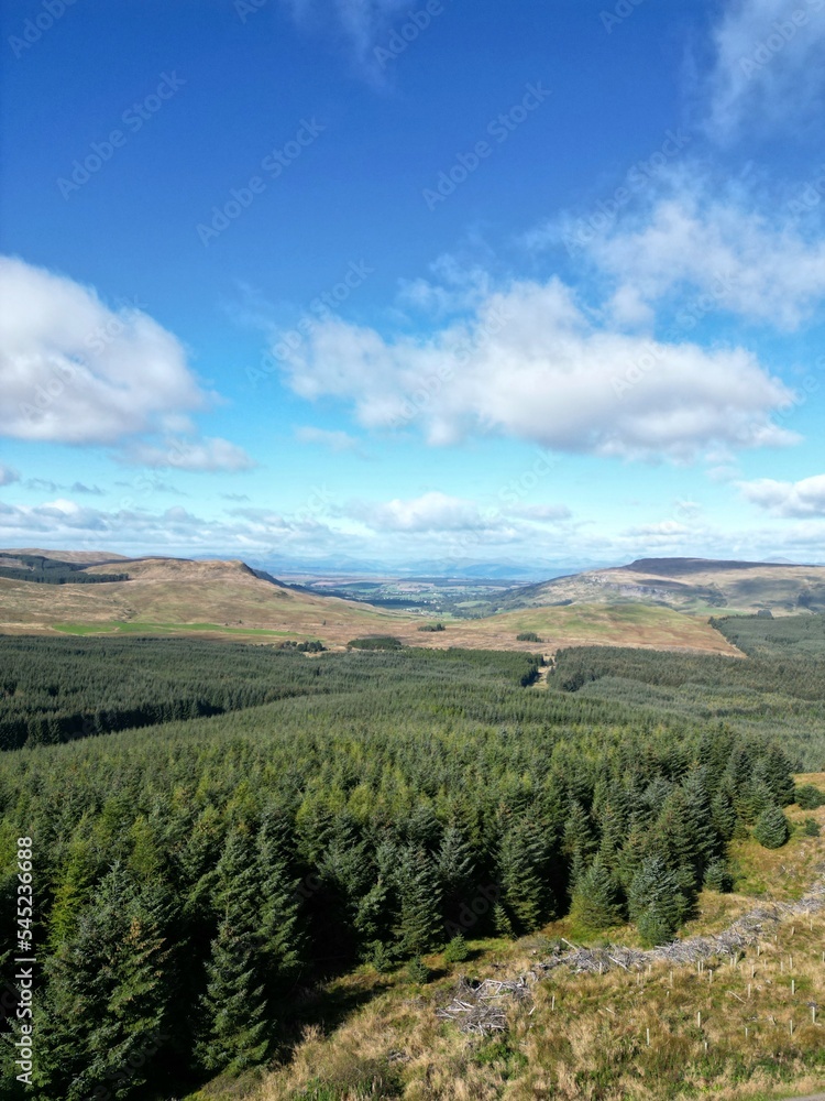 Obraz premium Vertical aerial view of Meikle Bin Hill, Carron Valley, and nearby green land in rural Scotland