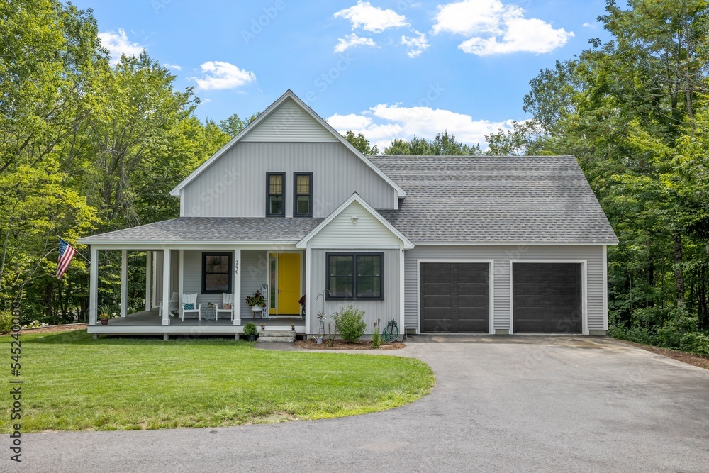 Fototapeta premium Modern custom new England colonial home with an American flag on a sunny day