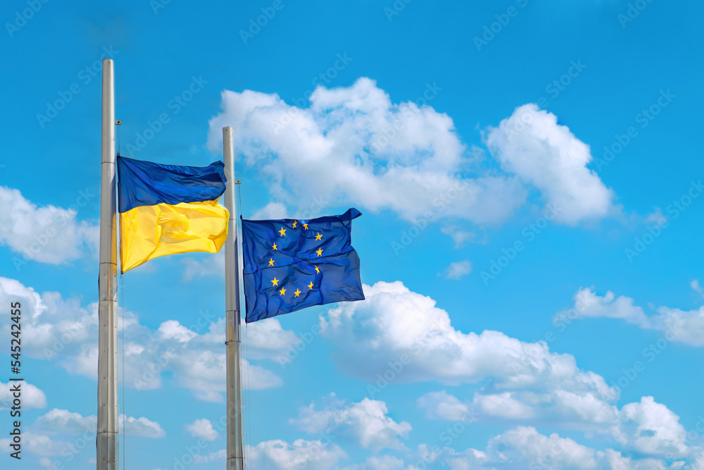 Flags of Ukraine and Europe on poles with blue sky Flags of Ukraine and Europe on poles with blue sky