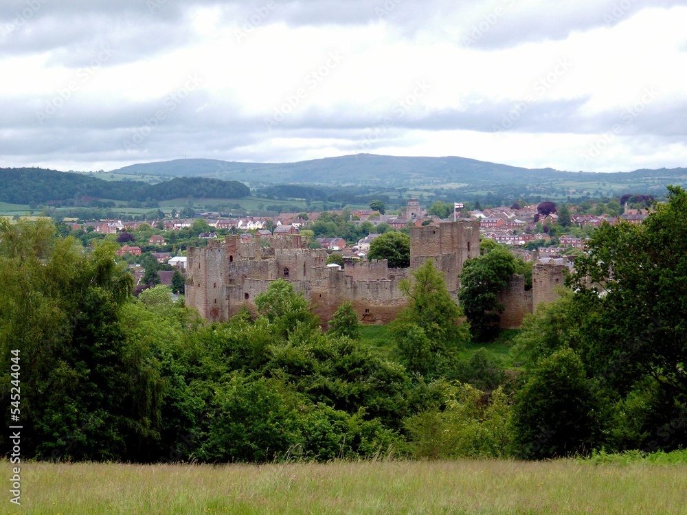 Ludlow castle with mountains in the background under a cloudy sky