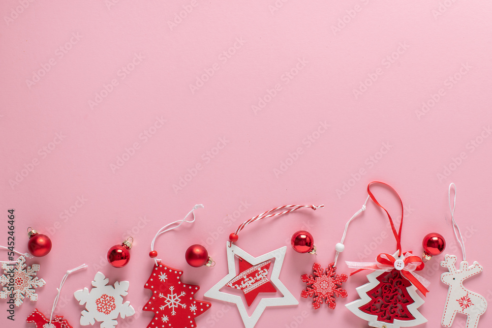 Christmas composition with red and white Christmas tree eco-toys at the bottom on a light pink background.