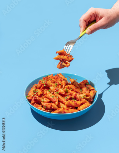 Penne pasta with spicy tomato sauce on a blue background.