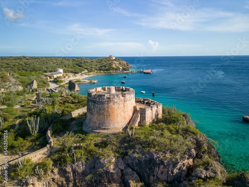 Aerial shot of a castle at Fort Beekenburg near Tugboat beach with blue seawater and skyscape photo