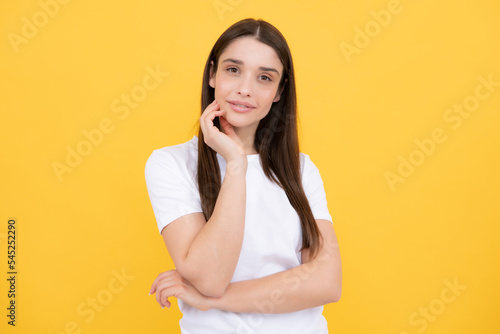 Pretty joyfully female model looking with satisfaction. Studio portrait of looking beautiful woman isolated against yellow background. photo