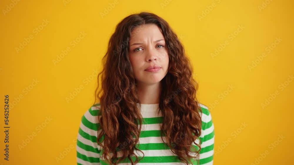 Bored curly haired brunette woman saying no at the camera in the yellow studio Bored curly haired brunette woman saying no at the camera in the yellow studio